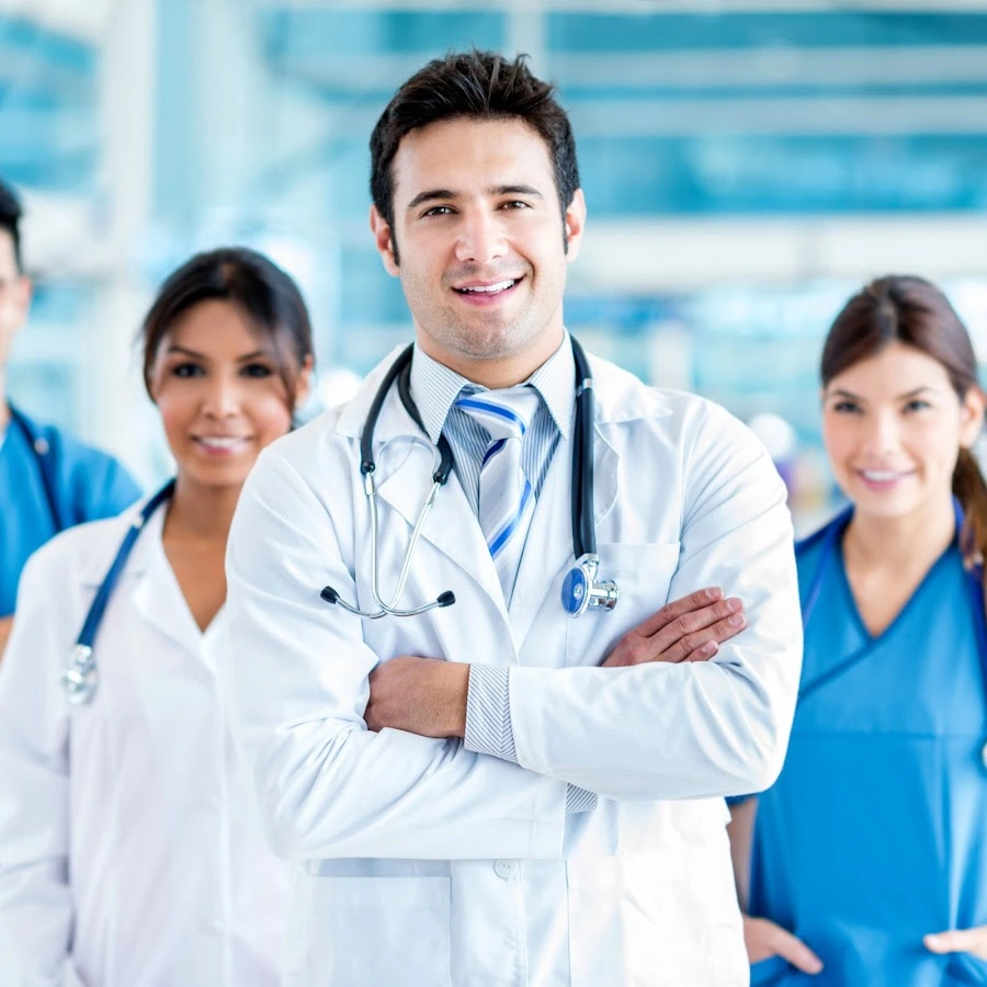 Male doctor with stethoscope in white coat standing with female medical staff members in clinical setting