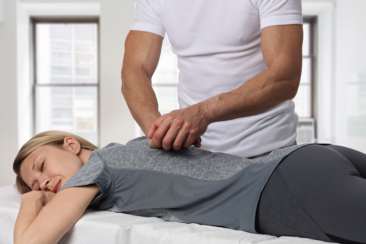 Chiropractor performing spinal manipulation on a patient lying face down