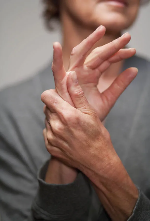 Person holding their hand with visible pain and redness in fingers and palm area