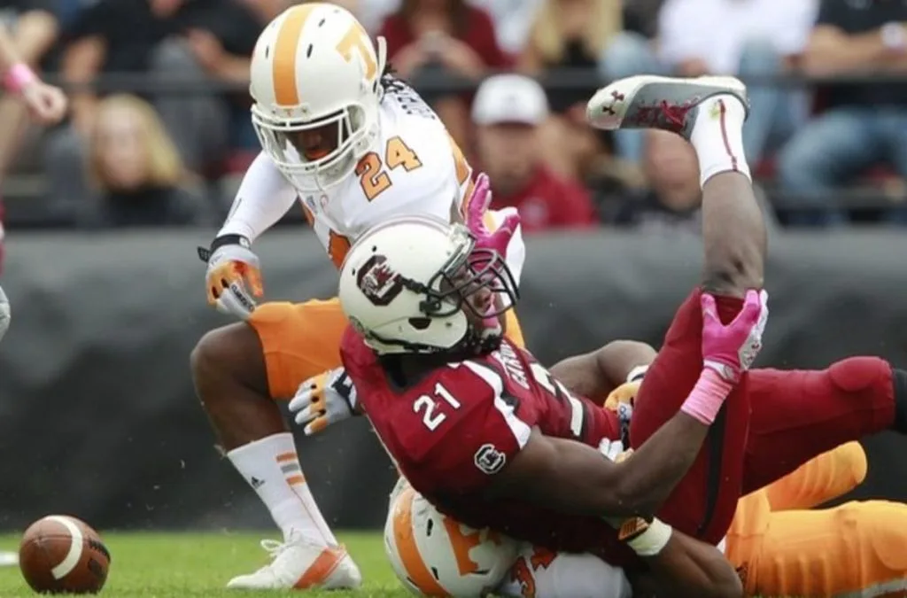 Football players colliding mid-play during a game, one airborne above the other