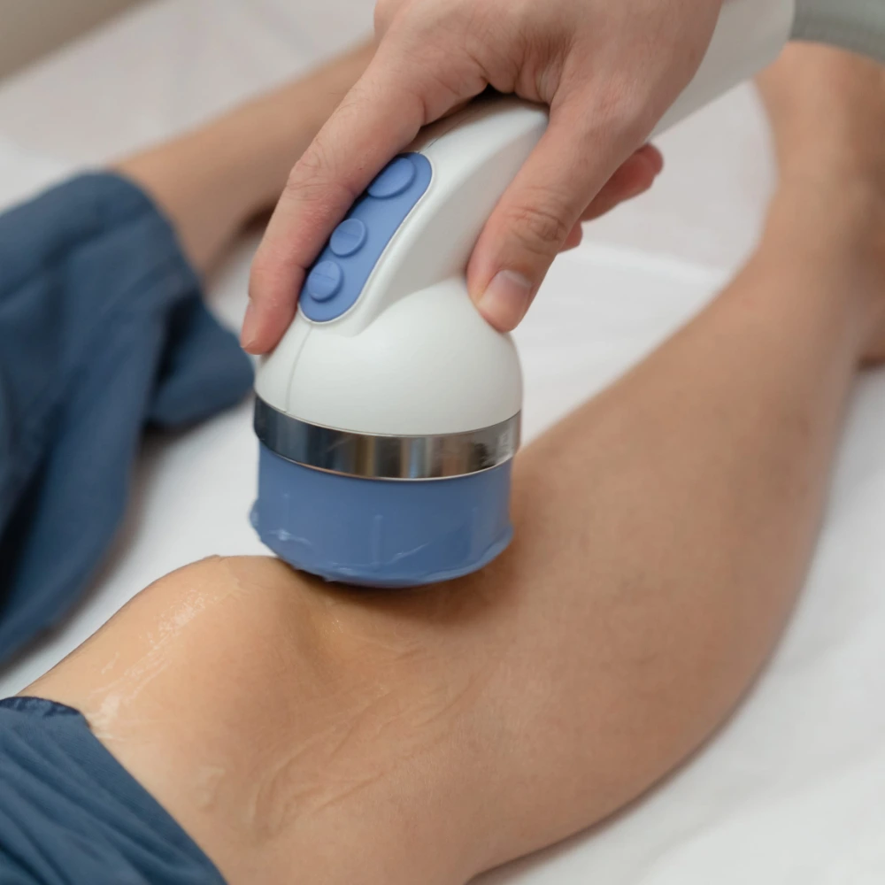 Practitioner using handheld ultrasound device on patient's knee