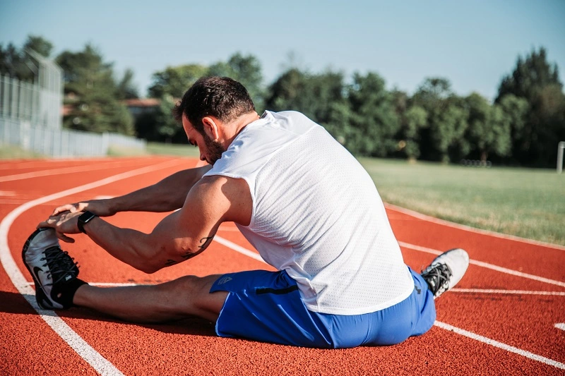 Athlete stretching hamstrings on a running track before training