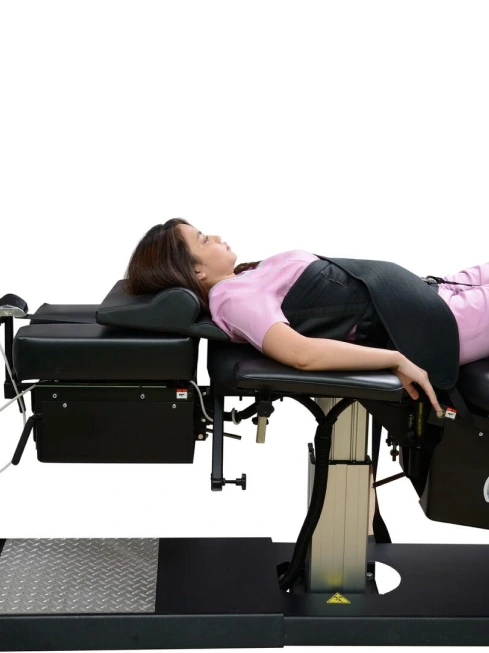 Patient lying on spine traction table during decompression therapy