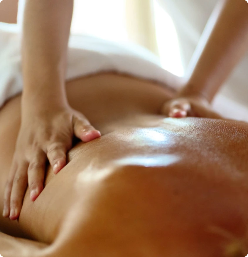 Massage therapist applying treatment to patient's back with oiled hands