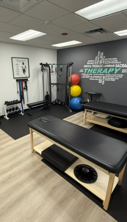 Physical therapy studio with exercise equipment including a multi-station machine, therapy balls, and a treatment table