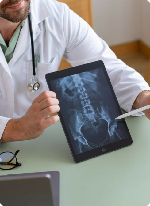 Doctor holding tablet displaying spinal x-ray image with stethoscope visible