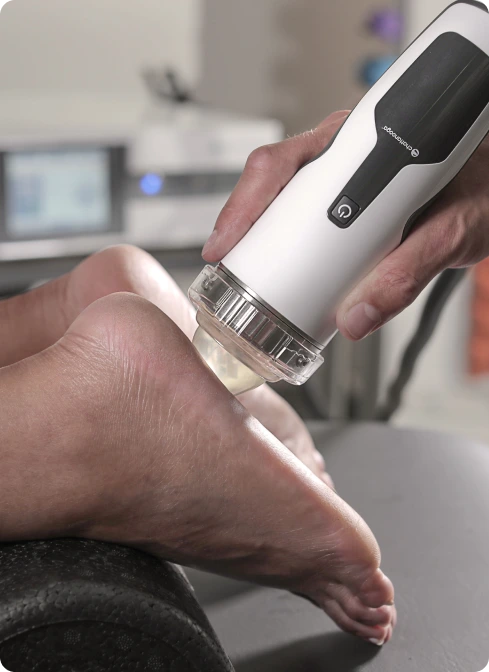 Practitioner holding thermal imaging device against patient's foot in clinical setting
