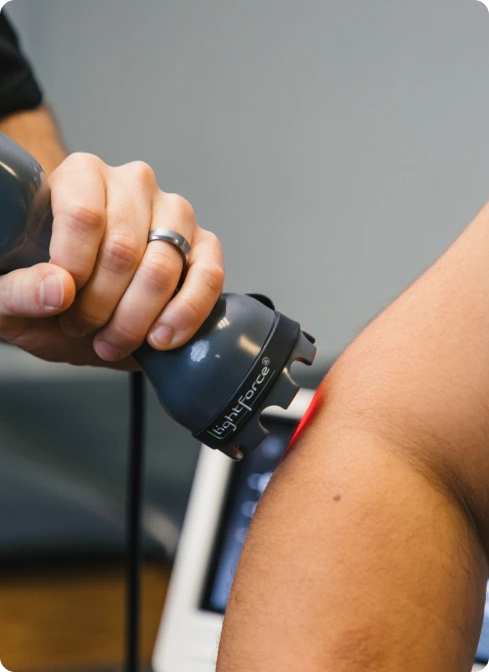 Practitioner using handheld therapeutic device on patient's shoulder