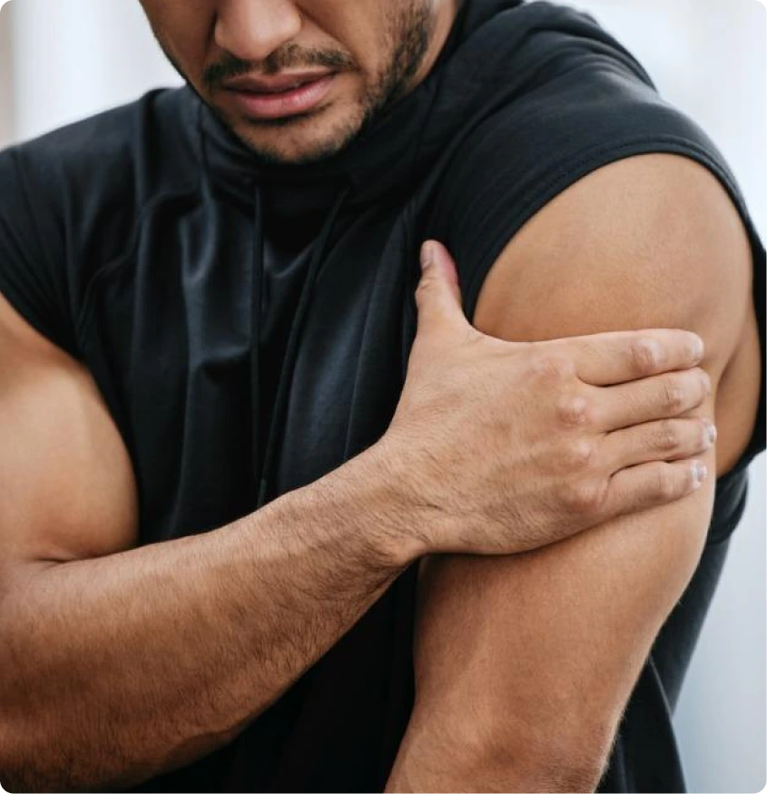 Man in black shirt touching his shoulder, expressing shoulder injury pain