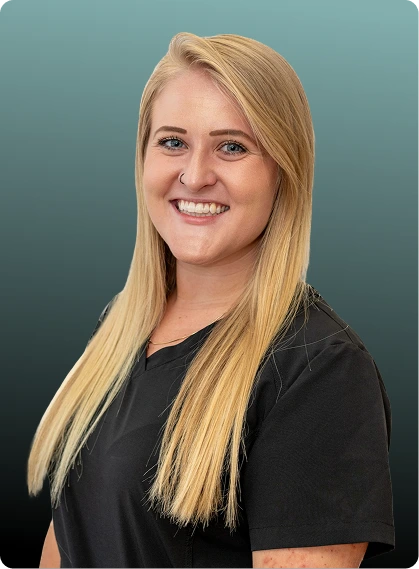 Woman with blonde hair wearing black shirt, smiling at camera against teal background