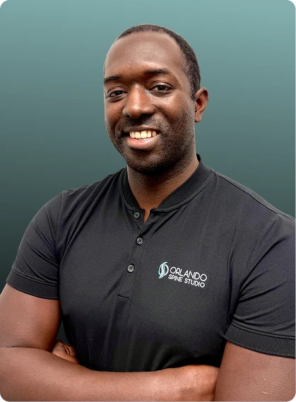 Man wearing Orlando Spine Studio branded black polo shirt, arms crossed, smiling at camera