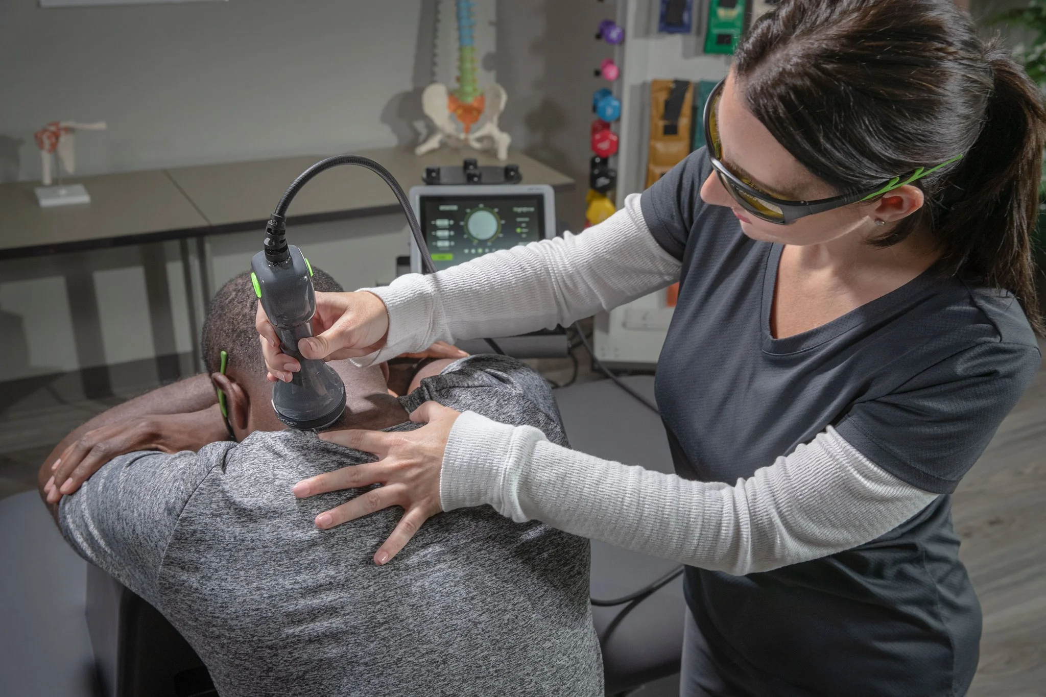 Clinician applies Class IV deep tissue laser therapy to a patient's neck and upper back